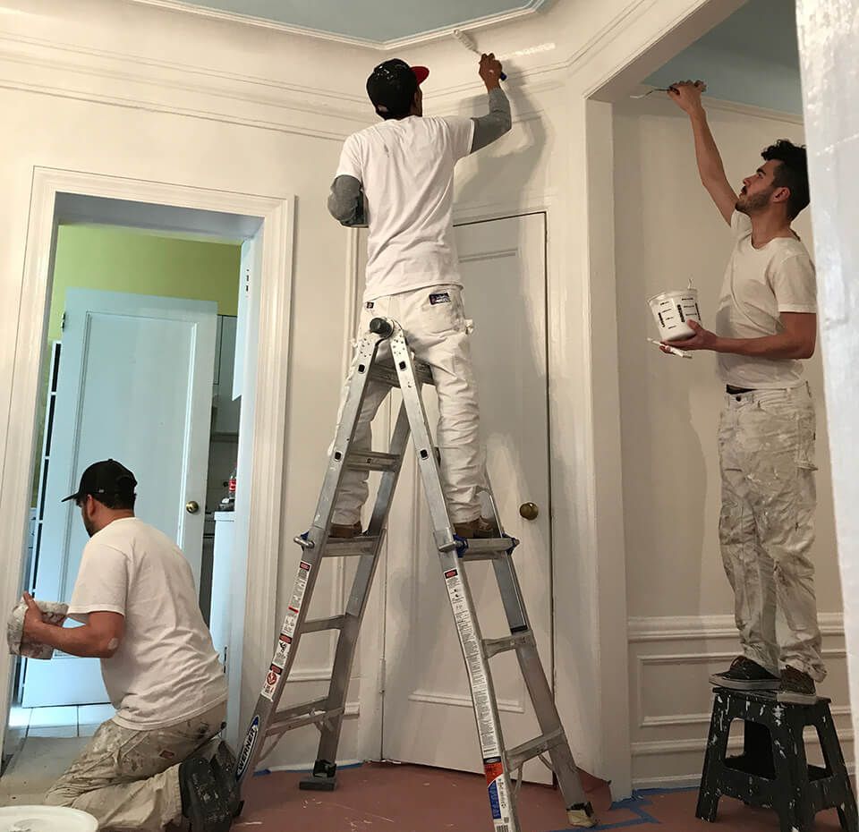 Painting team painting a room white
